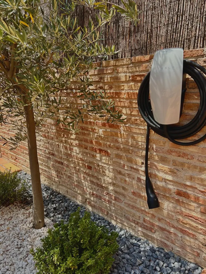 Tesla Wall Connector instalado sobre un muro de ladrillo